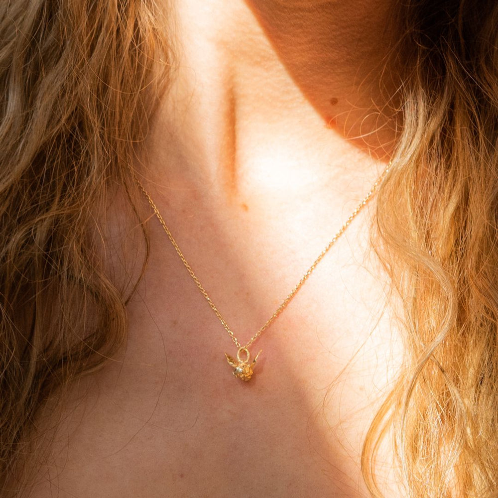 The Bee in Flight Necklace displayed on a model, highlighting the necklace's elegance and fine trace chain.