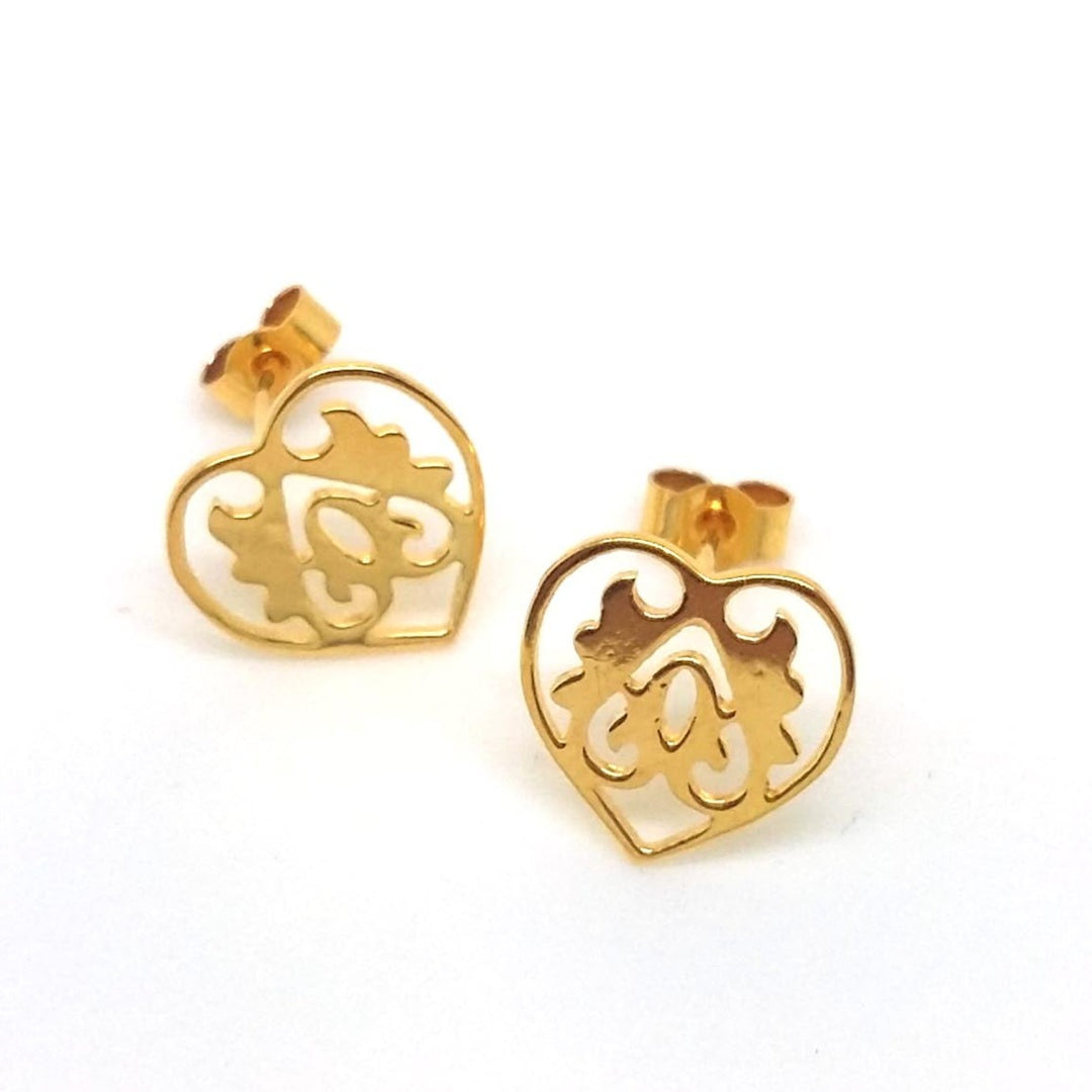 A pair of gold vermeil stud earrings in the shape of an ace of hearts, with intricate detailing and a round hook at the back for attachment.