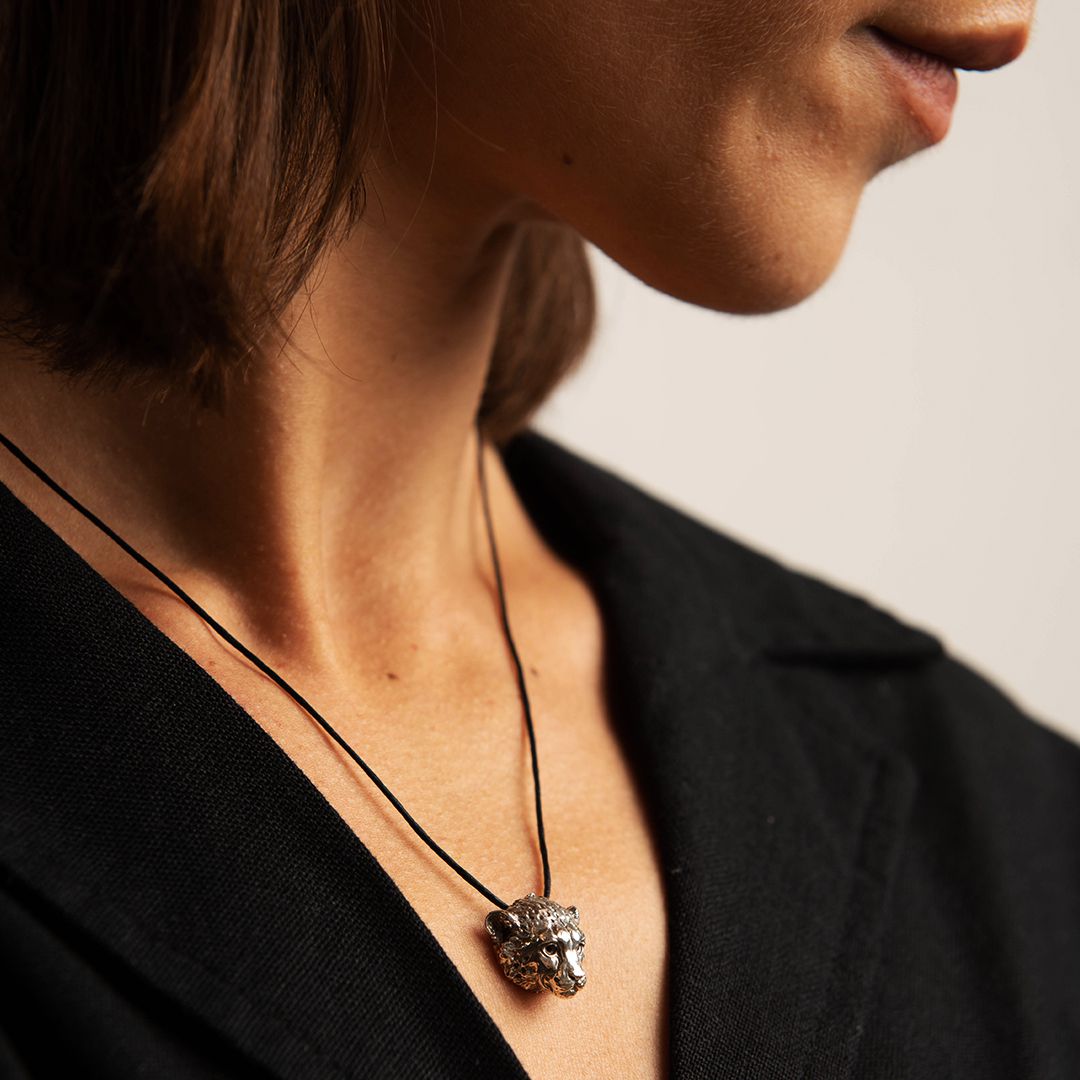Model wearing the Cheetah Necklace layered over a neutral top, showcasing the elegant, handmade pendant inspired by the endangered cheetah, with a warm natural glow.
