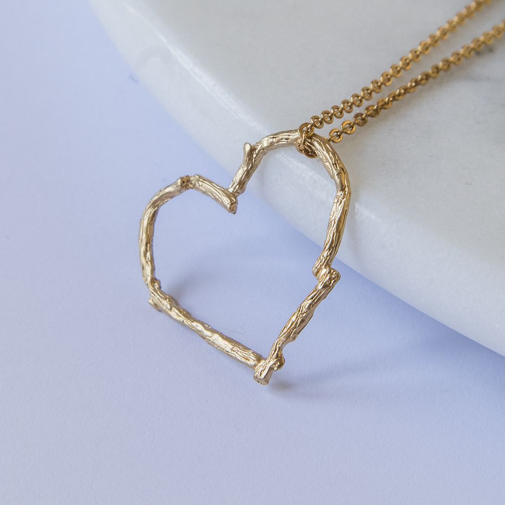 Blackbird Jewellery A gold vermeil heart-shaped necklace pendant with a twig effect, displayed against a white background.