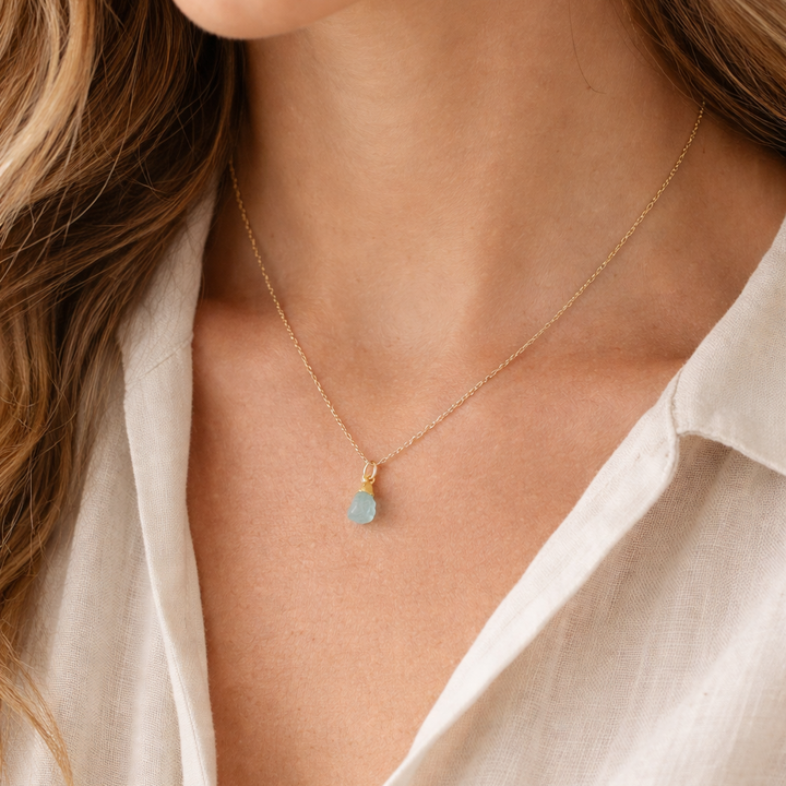 Blackbird Jewellery Gold Vermeil Raw Aquamarine Crystal Necklace worn by a female model with an ivory linen blouse in soft natural light