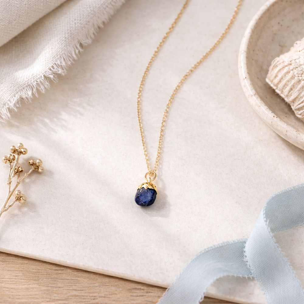 Blackbird Jewellery Gold Vermeil Raw Blue Gemstone Necklace styled on a soft neutral flat lay with linen, ceramic dish and pale blue ribbon