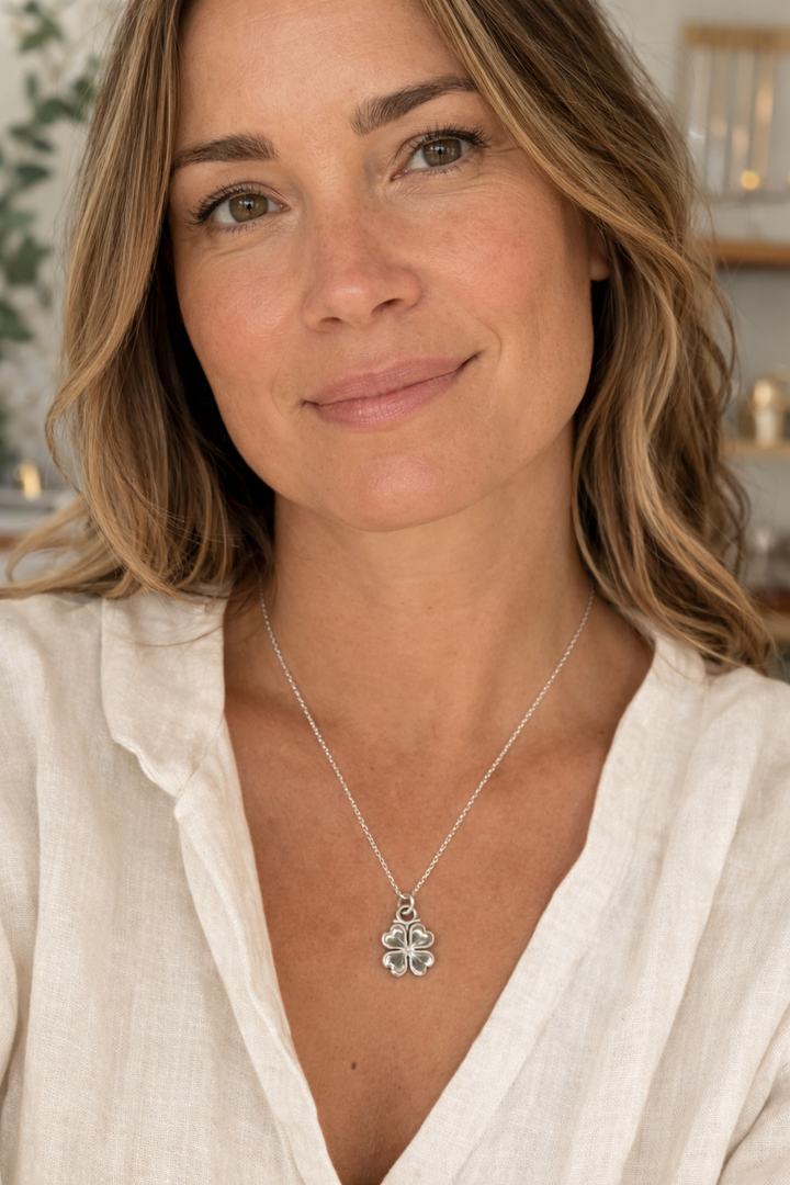 Blackbird Jewellery sterling silver four leaf clover necklace worn by a woman in a natural studio setting, handcrafted lucky clover charm necklace inspired by Irish symbolism.