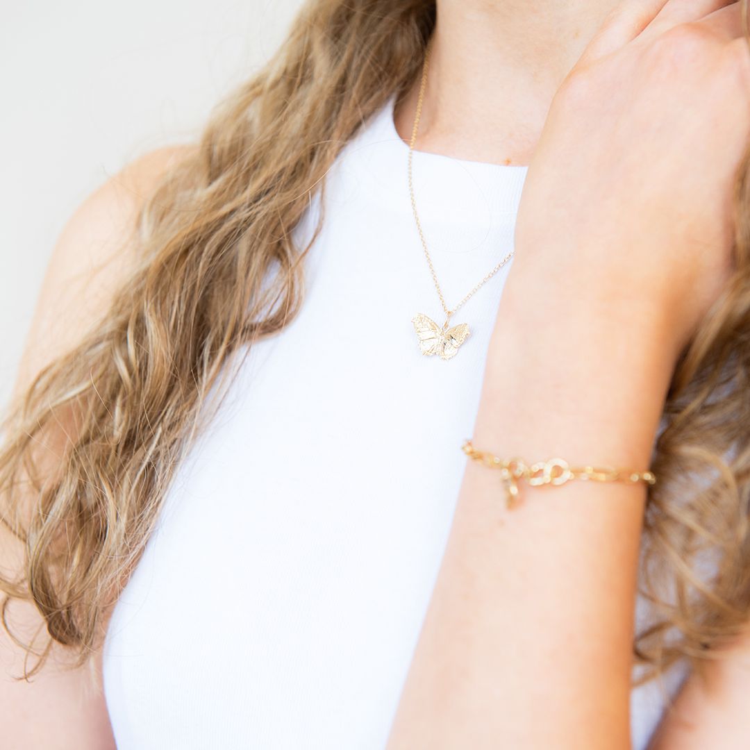 Blackbird jewellery Model wearing delicate gold butterfly necklace at collarbone.