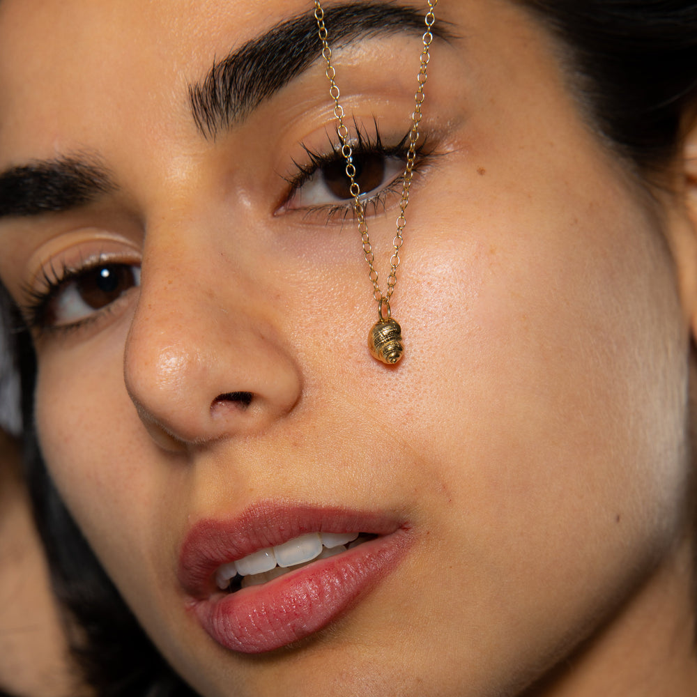 Model wearing gold winkle shell necklace on 45cm chain, coastal layering style.