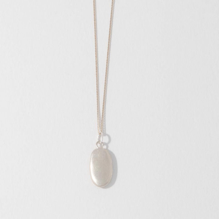 A sterling silver pebble charm necklace with a sateen finish on a white background.