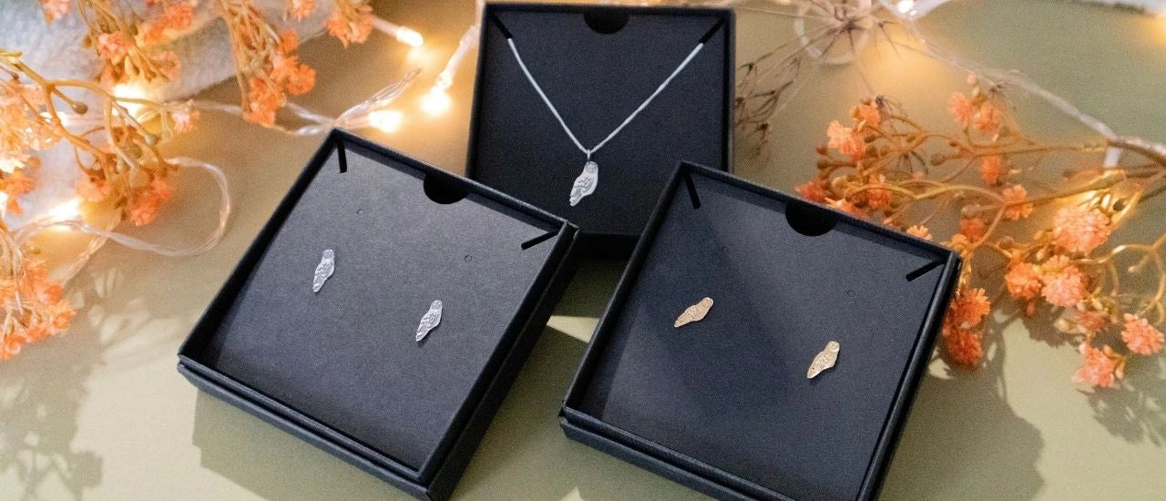 Soft Christmas gifting scene with Blackbird Jewellery gift boxes and a sterling silver barn owl necklace. Warm, handmade jewellery gift packaging perfect for gifting.