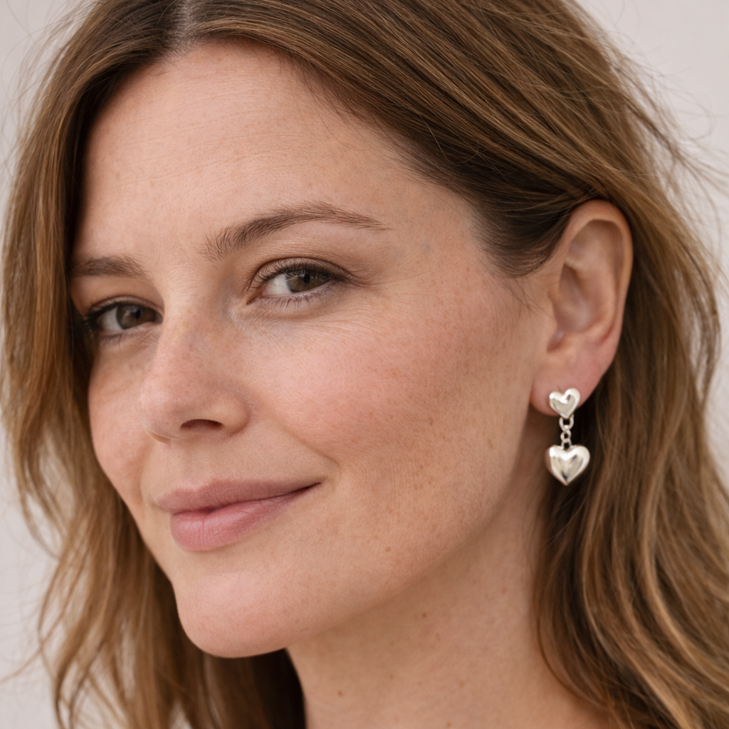 Woman wearing Blackbird Jewellery heart-shaped earrings with a neutral background