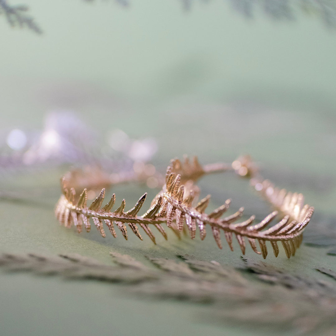 Licensed To Charm gold vermeil fern hoop earrings on green botanical backdrop