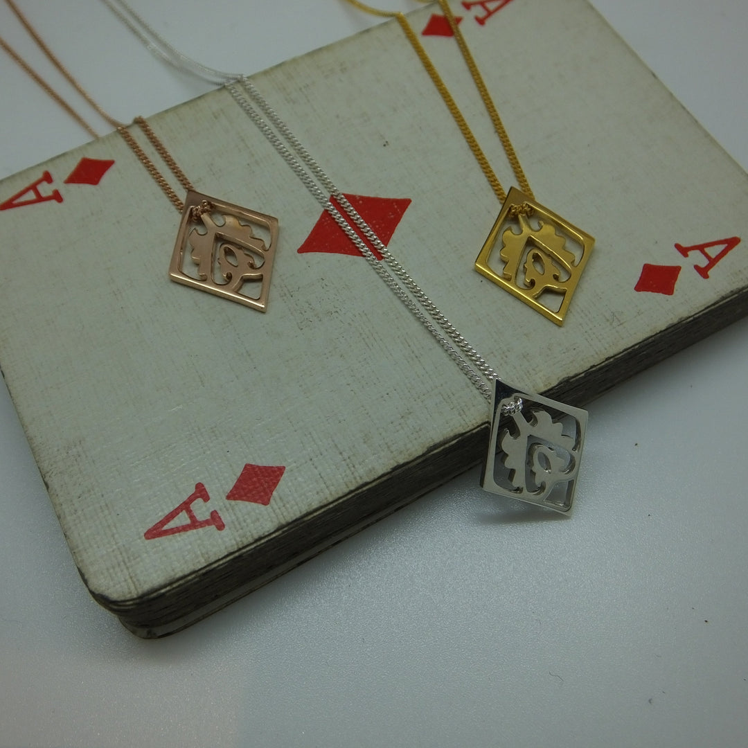 Gold and silver necklace draped over a deck of cards with red diamond suits.