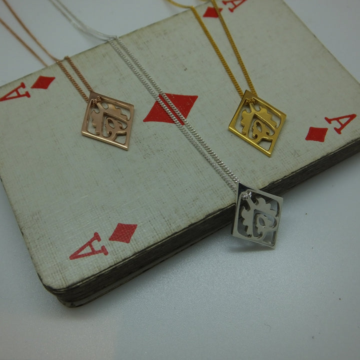Gold and silver necklace draped over a deck of cards with red diamond suits.