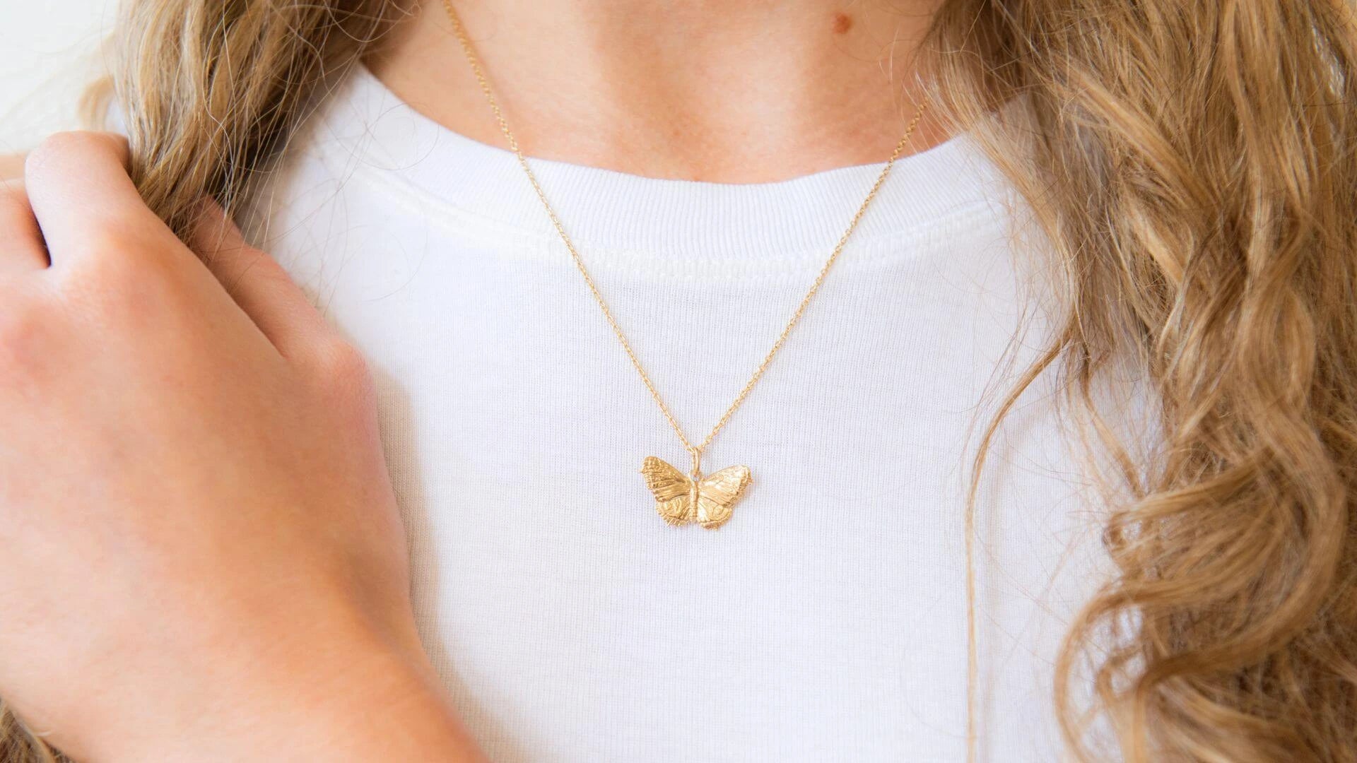 Gold butterfly necklace worn by a person with a blurred background