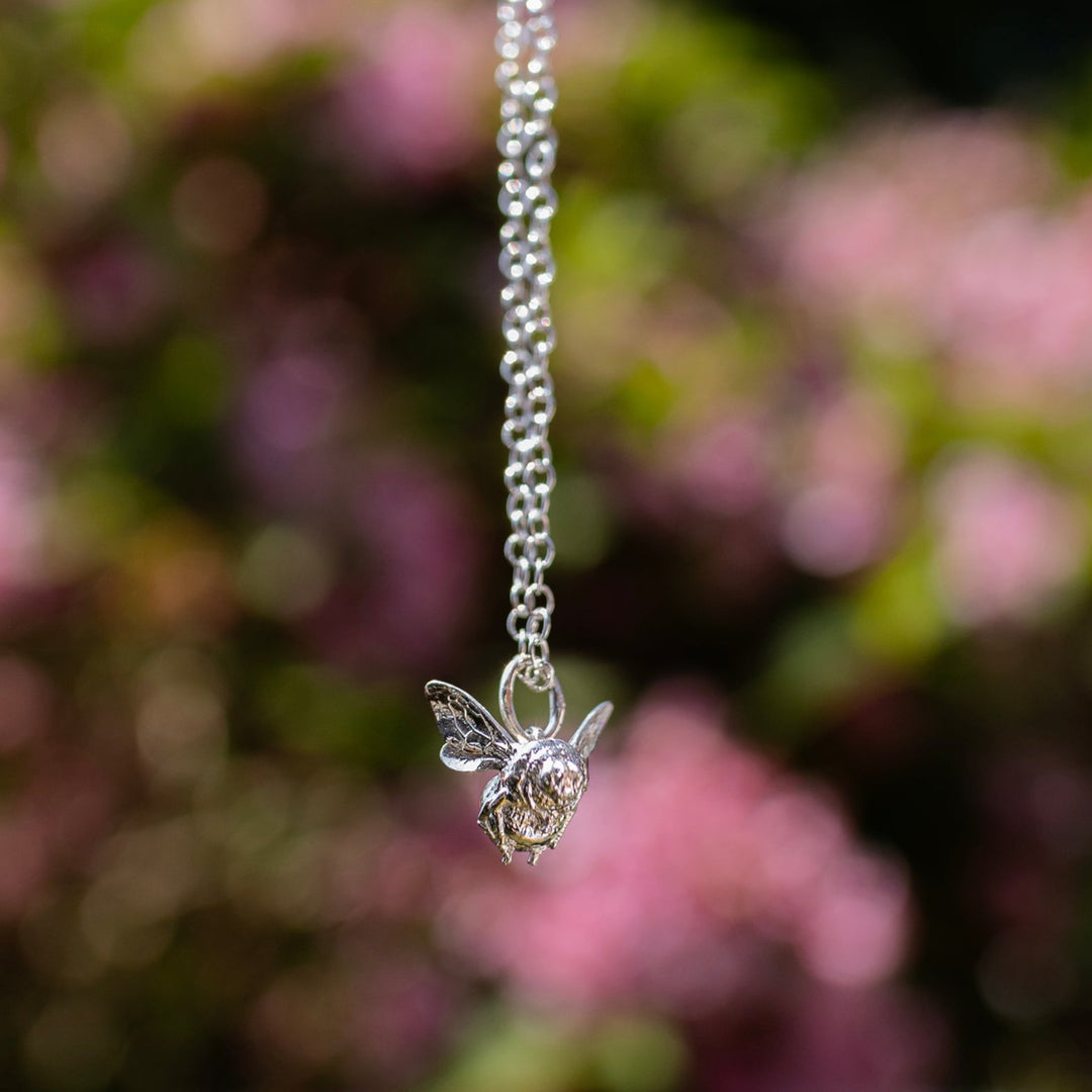 Close-up of the Bee in Flight Necklace in recycled sterling silver, showcasing the intricate bee charm with detailed wings and stripes.