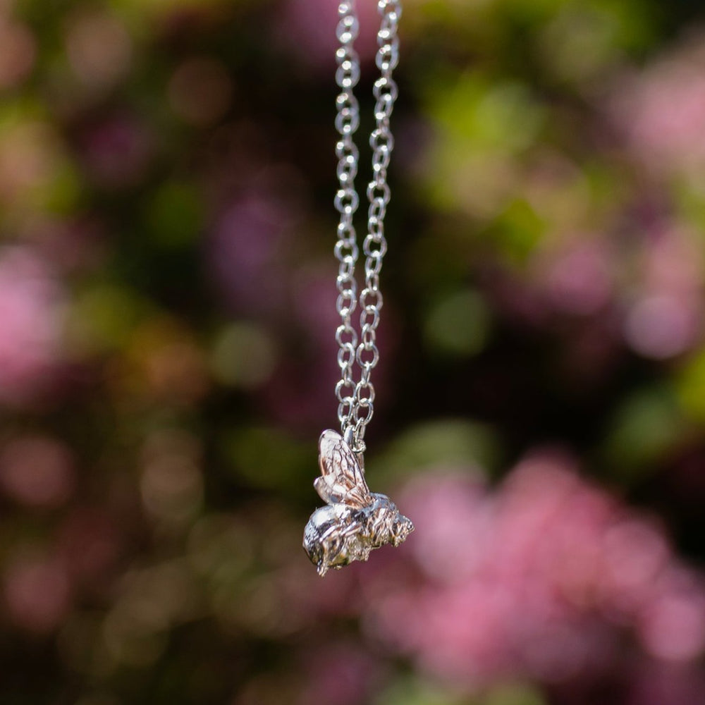 The Bee in Flight Necklace displayed on a model, highlighting its elegance and fine trace chain in sterling silver.