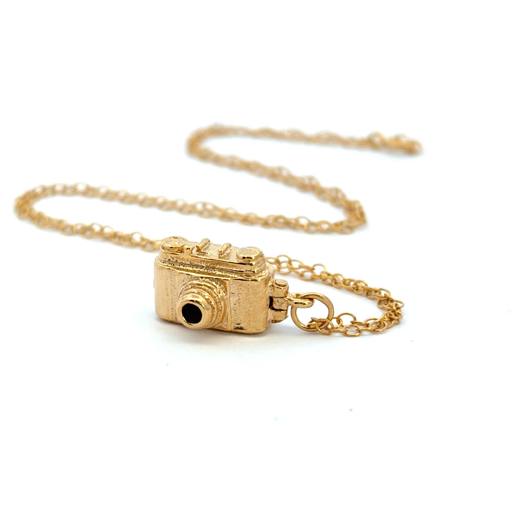 18ct gold vermeil vintage camera necklace laid out on its chain on a pale background