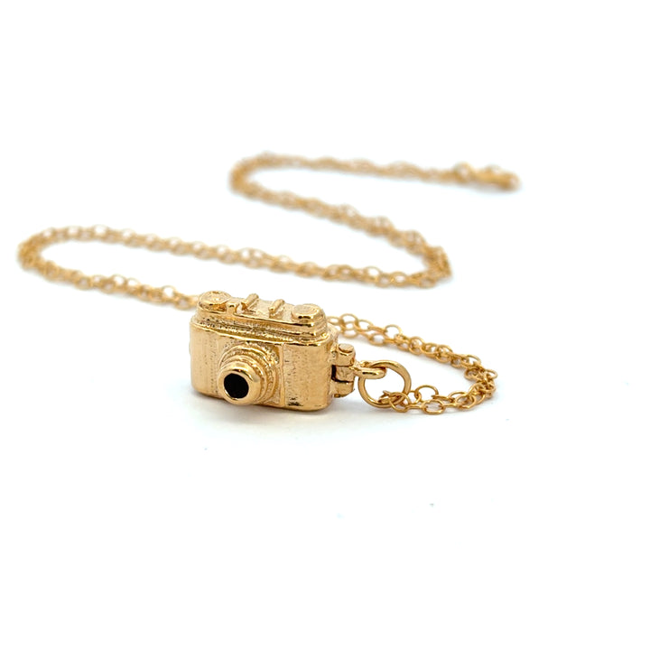 18ct gold vermeil vintage camera necklace laid out on its chain on a pale background