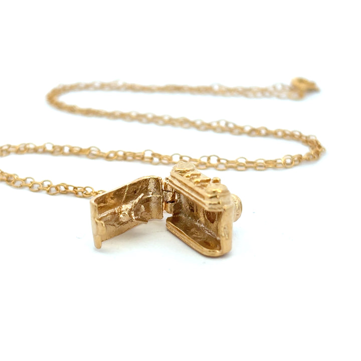 Close-up side view of an 18ct gold vermeil vintage camera pendant on a chain