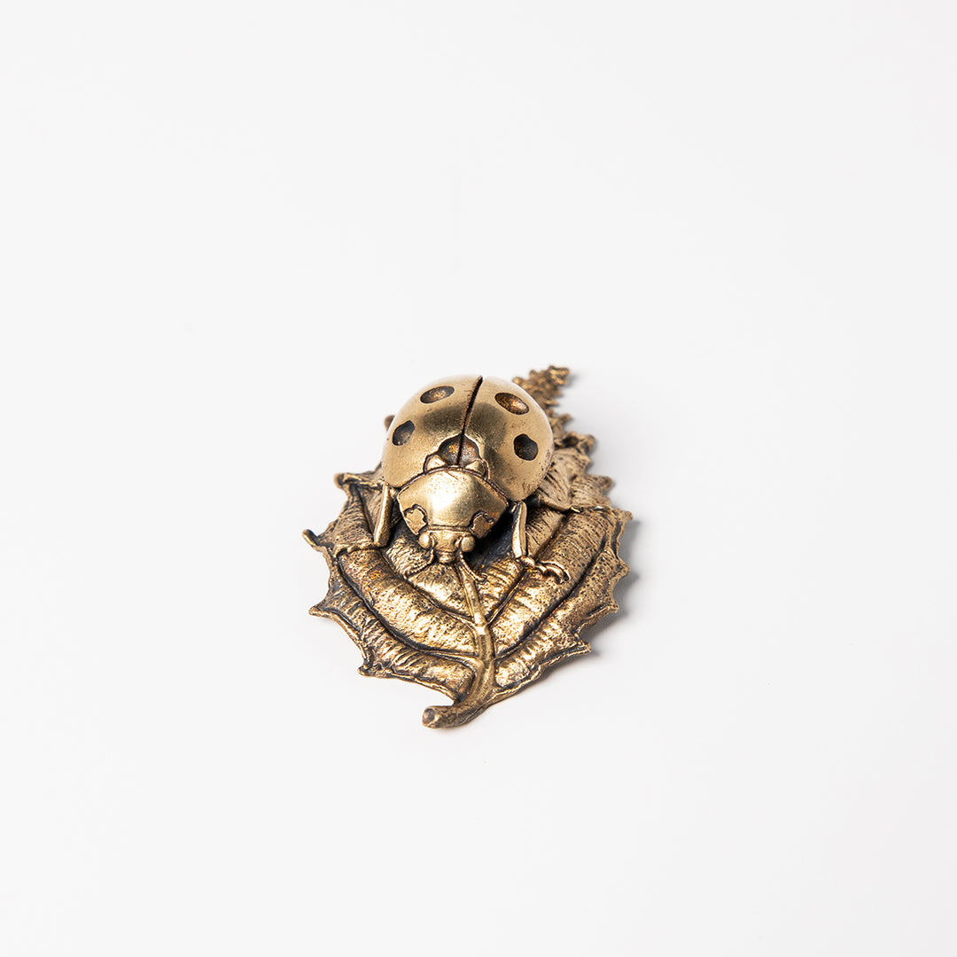 Handcrafted bronze ladybird sculpture with detailed wings and leaf perch