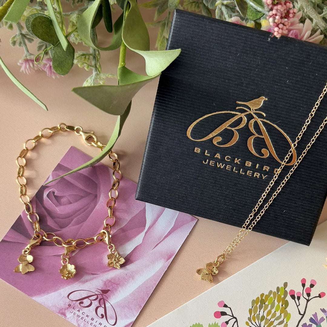 Handmade primrose clip-on charm clipped onto gold vermeil belcher bracelet with violet and daisy charms by Blackbird Jewellery