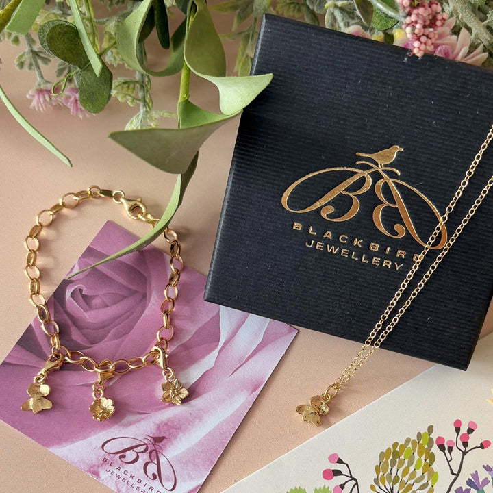 Handmade primrose clip-on charm clipped onto gold vermeil belcher bracelet with violet and daisy charms by Blackbird Jewellery