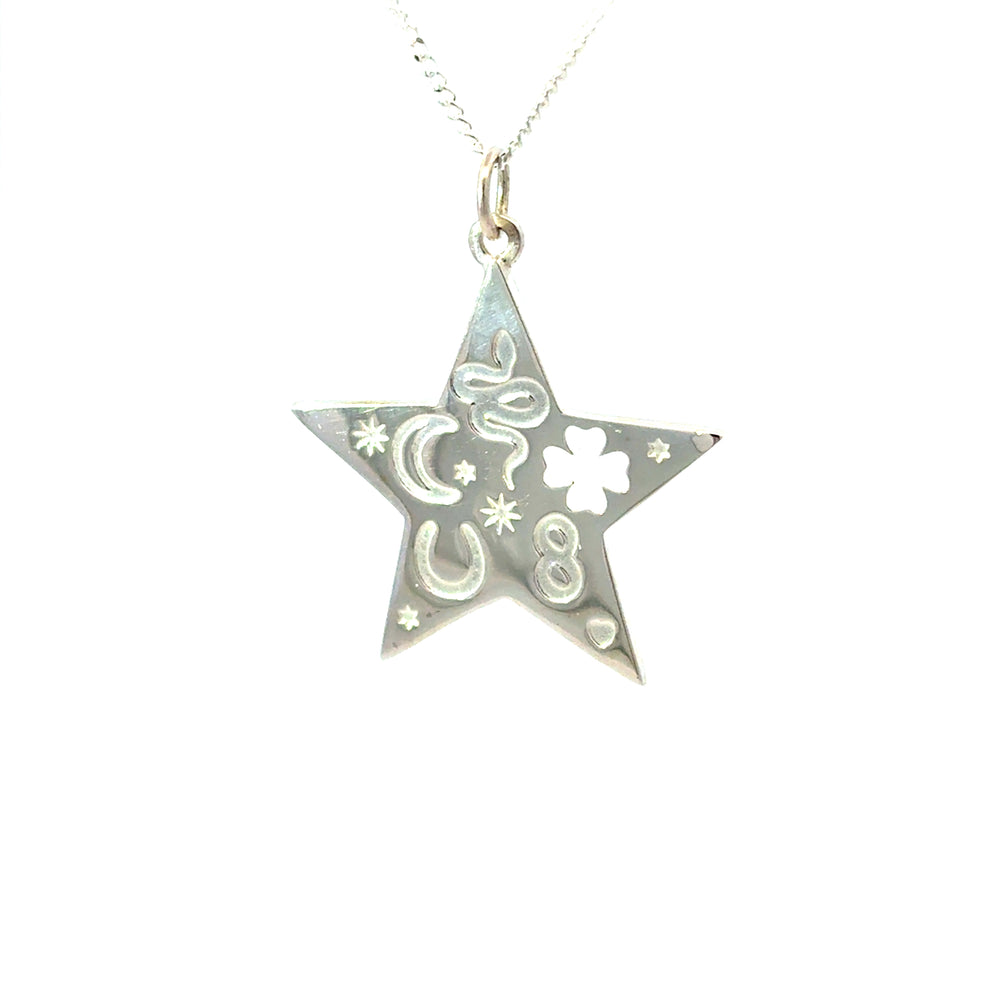 Close-up of silver star pendant with moon, stars, horseshoe and clover