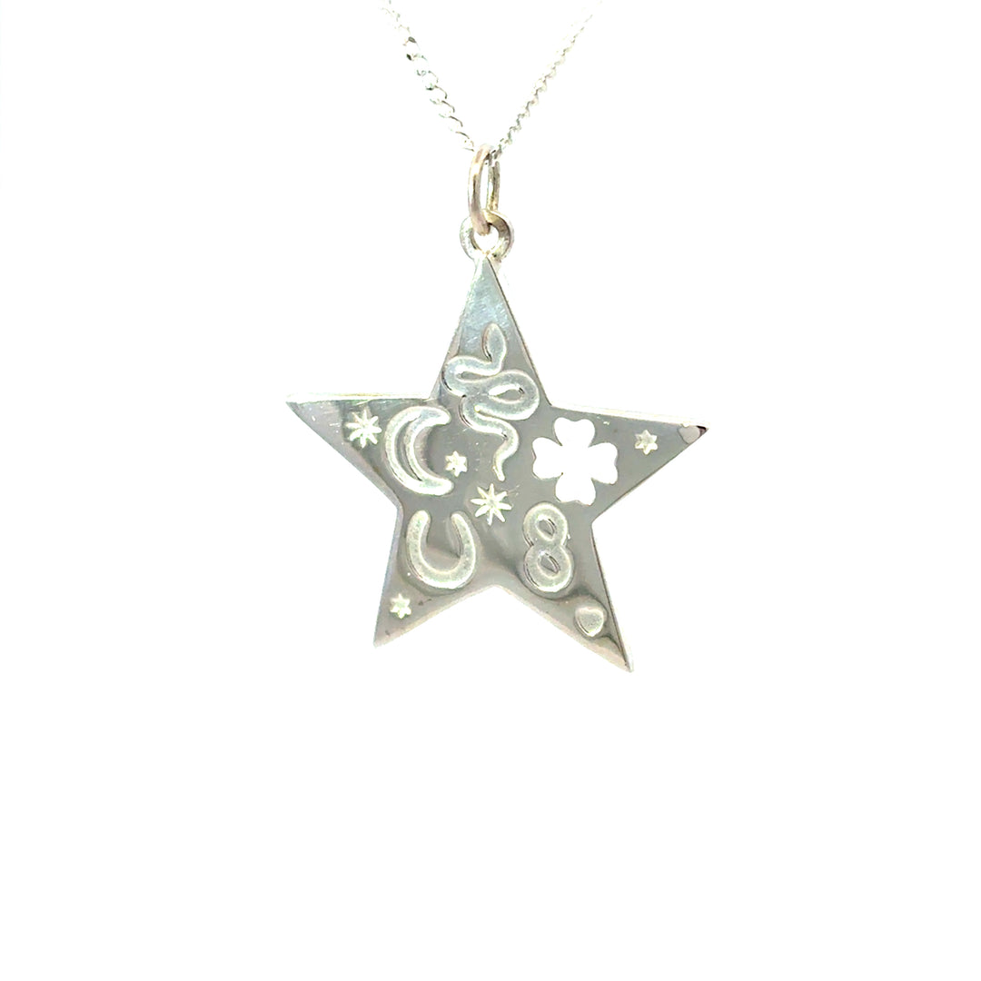 Close-up of silver star pendant with moon, stars, horseshoe and clover