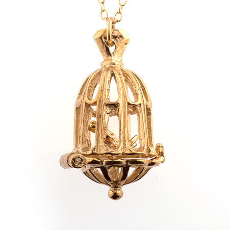 Close-up of an intricately detailed gold vermeil birdcage pendant housing a delicate bird, perfect for gifting or everyday elegance.